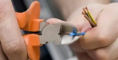licensed electrician performing precise wire cutting and preparation during electrical service in Modesto, CA