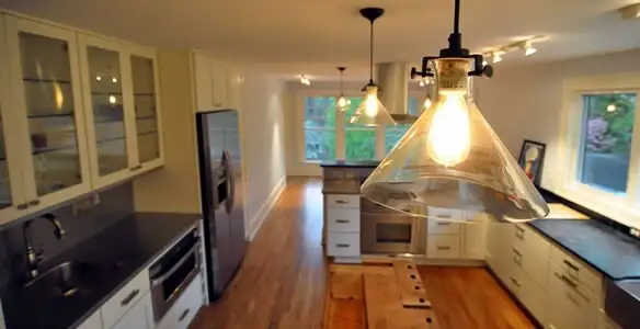 Residential electrician installing modern indoor light fixture in a home in Modesto, CA