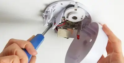 Certified technician wiring smoke detector during installation in Modesto, CA